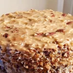 German Chocolate Pound Cake topped with gooey coconut pecan frosting on a rustic cake stand