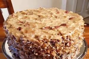 German Chocolate Pound Cake topped with gooey coconut pecan frosting on a rustic cake stand