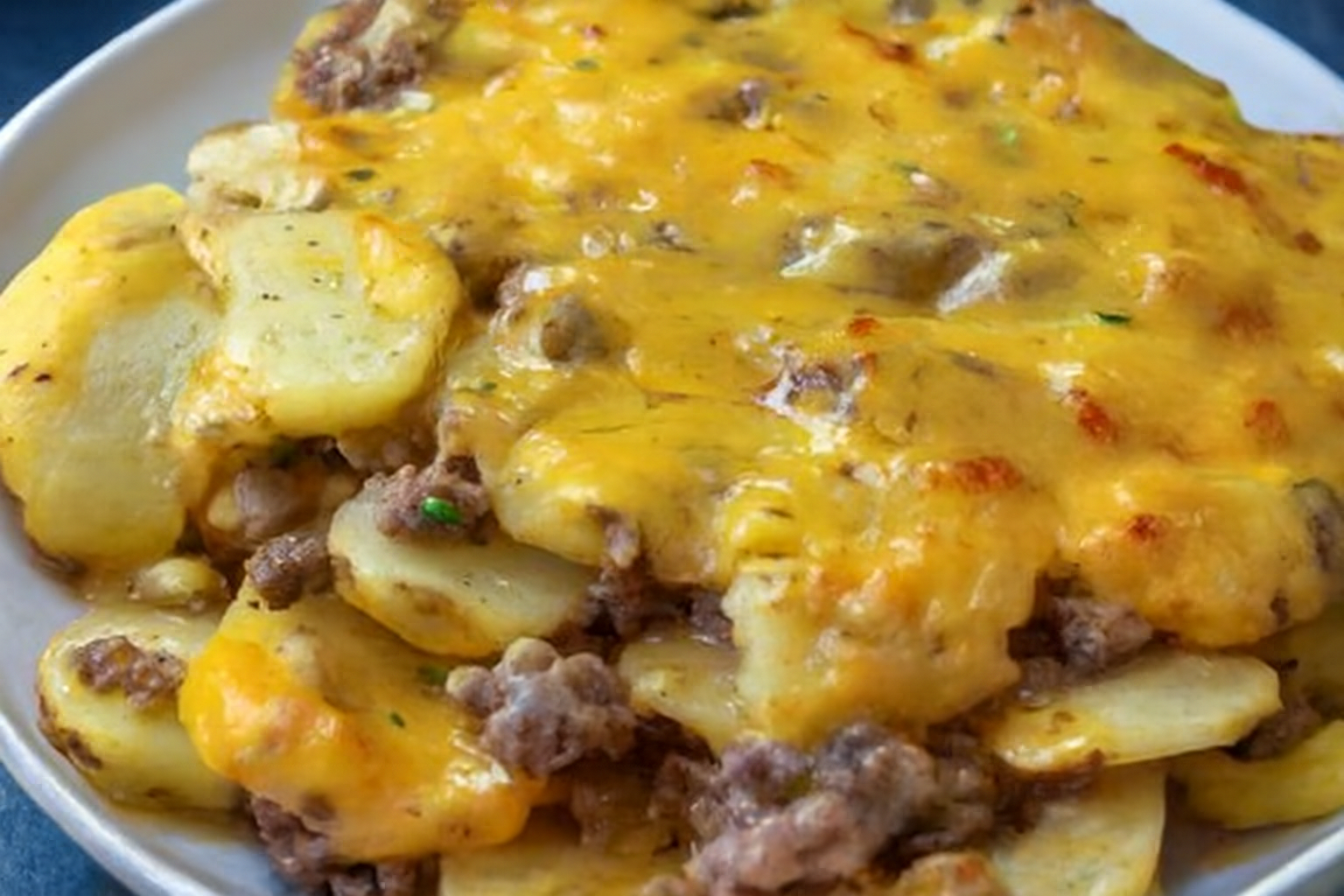 Cheesy hamburger potato casserole recipe with ground beef, sliced potatoes, and melted cheddar cheese baked to golden perfection