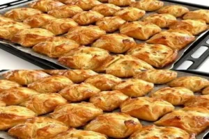 Golden brown mini puff pastry parcels filled with cheese and spinach on a baking tray