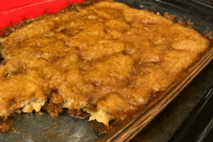 Pecan Pie Cobbler with gooey pecan filling and golden buttery crust topped with pecan halves, served warm with vanilla ice cream.