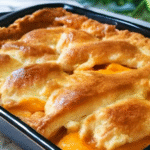 Triple crust peach cobbler recipe baked with layers of pie crust, sweet peach filling, and golden flaky topping in a baking dish