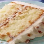 southern butter pecan layer cake slice with frosting and pecans