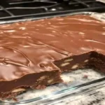 chocolate walnut fudge with glossy chocolate topping and crunchy walnuts in a glass baking dish