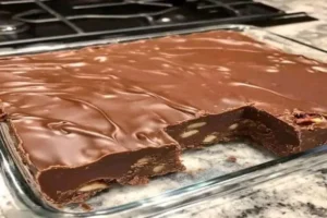 chocolate walnut fudge with glossy chocolate topping and crunchy walnuts in a glass baking dish