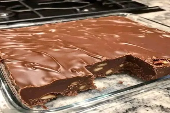 chocolate walnut fudge with glossy chocolate topping and crunchy walnuts in a glass baking dish